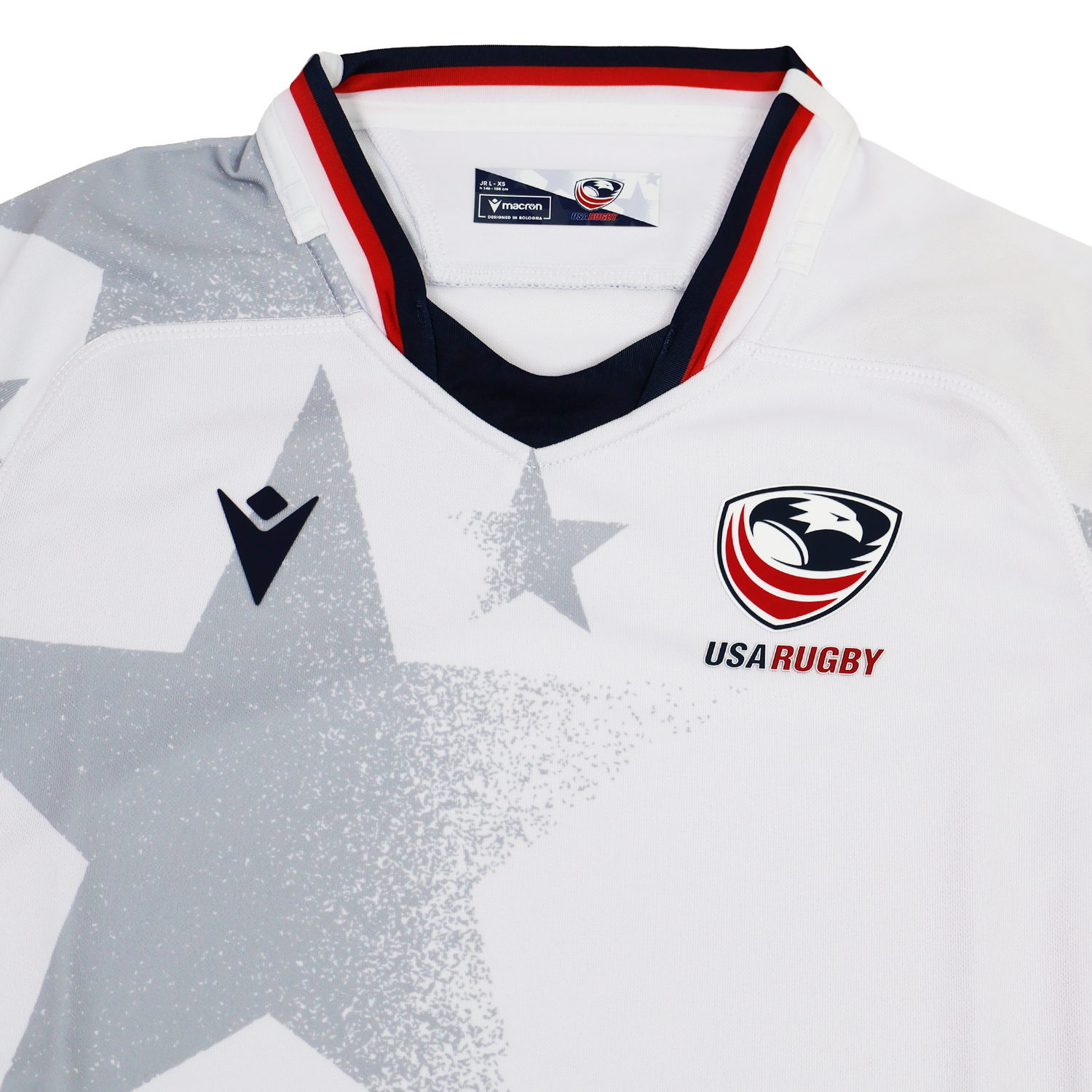The Youth USA Rugby 24/25 Away Jersey by Macron features a white base with a bold gray star pattern, USA Rugby and Macron logos on the chest, and red, white, and blue collar trim.