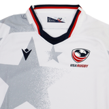 The Youth USA Rugby 24/25 Away Jersey by Macron features a white base with a bold gray star pattern, USA Rugby and Macron logos on the chest, and red, white, and blue collar trim.