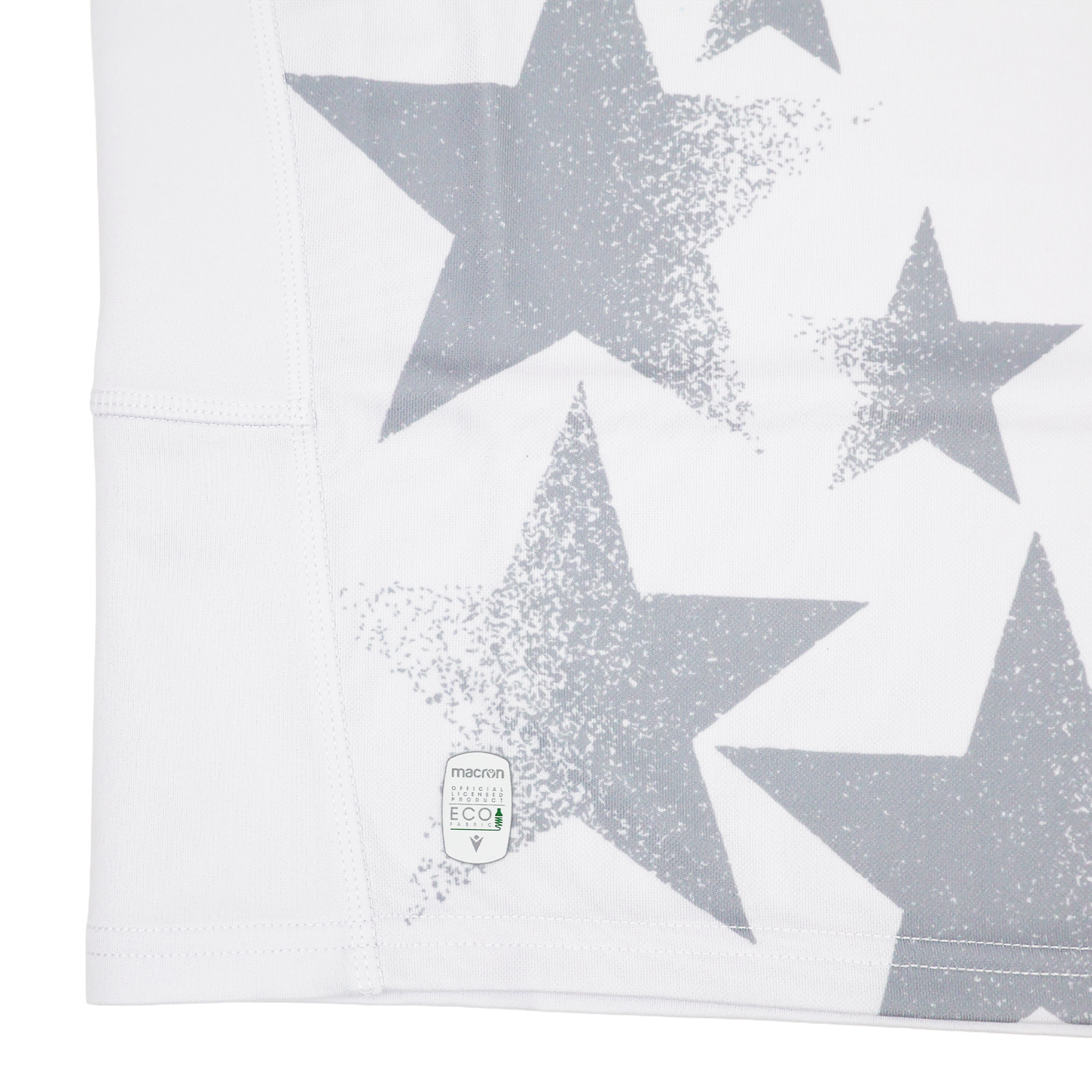 Close-up of white fabric with large and small gray stars, like the Youth USA Rugby 24/25 Away Jersey by Macron, featuring a small eco-friendly label near the hem.