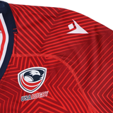 Close-up of the USA Rugby 24/25 Red Replica Training Jersey by Macron, showcasing a geometric pattern, the eagle logo, and a white Macron logo on the shoulder.