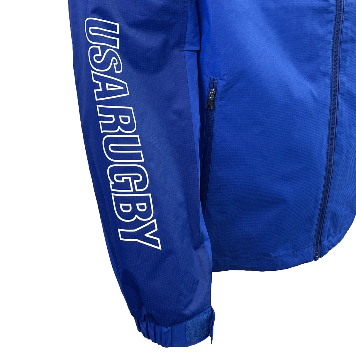 The USA Rugby 25 Player Waterproof Jacket by Macron is blue, has a side zip pocket, and "USA RUGBY" printed in white on the left sleeve.