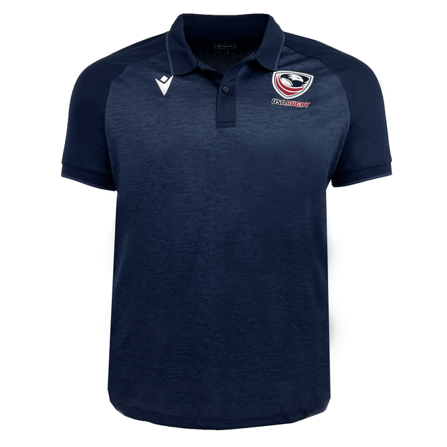 The USA Rugby 25 Travel Poly Polo by Macron is a navy blue, short-sleeve polo featuring the USA Rugby logo on the left chest and a white Macron logo on the right chest.