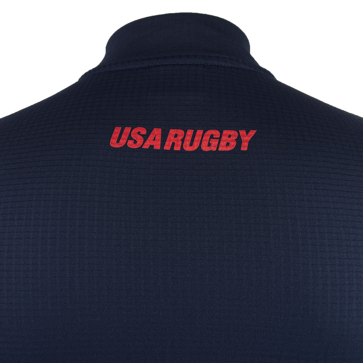 Close-up of the back of the USA Rugby 25 Travel 3D Full-Zip Top by Macron, featuring "USA RUGBY" in red capital letters near the collar.