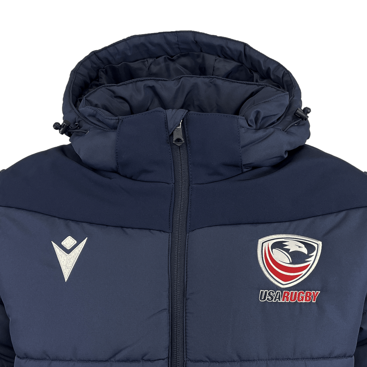 The USA Rugby 25 Padded Jacket by Macron is navy blue with a hood, featuring the USA Rugby logo on the right chest and a white Macron chevron logo on the left chest.
