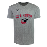 The USA Rugby 25 Leisure T-Shirt by Macron features "USA Rugby" text in red and a stylized eagle rugby ball logo on the front.
