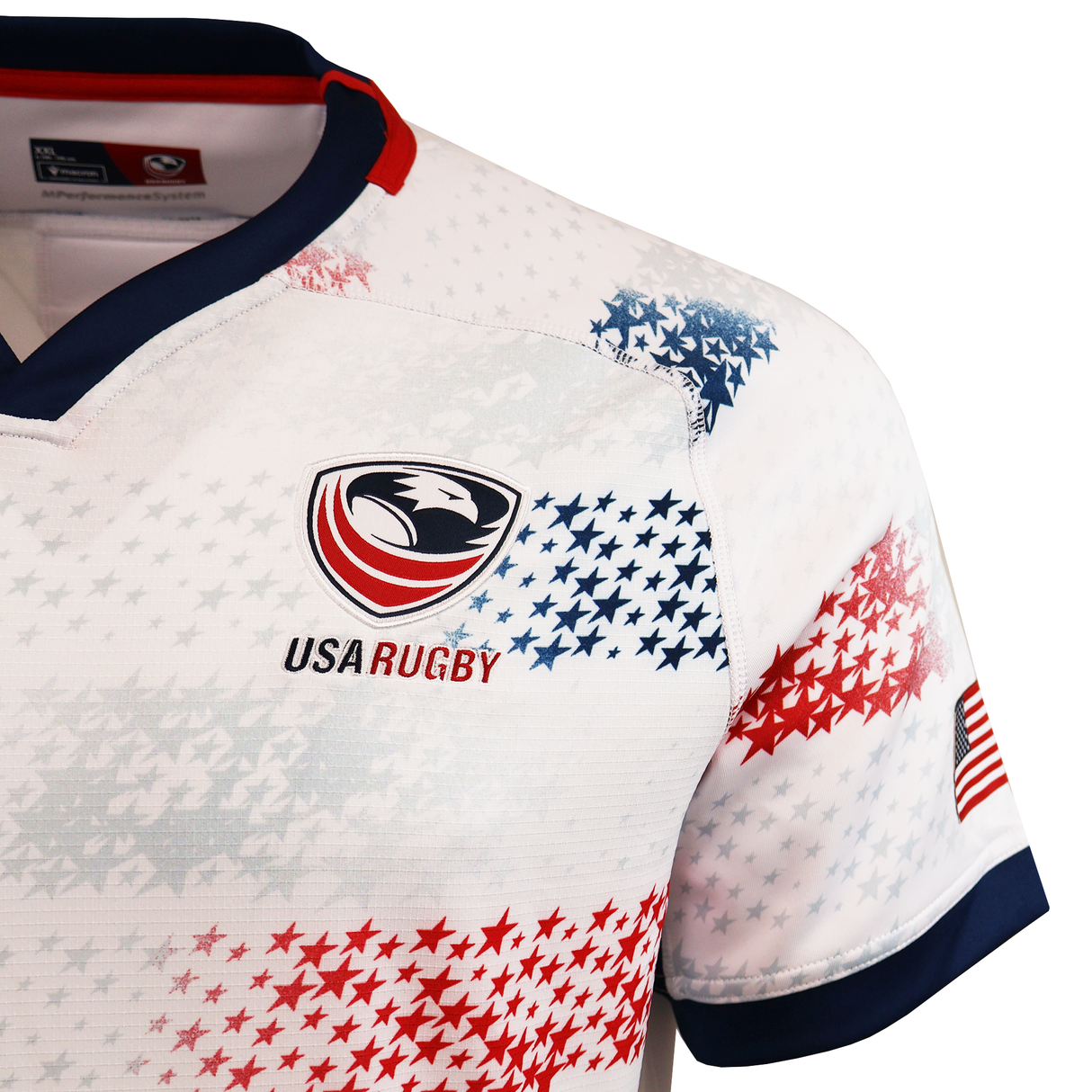 Close-up of the USA Rugby 25/26 Home Body Fit Match Jersey by Macron: a white rugby shirt with red and blue star patterns, eagle logo, and small American flag on the sleeve.