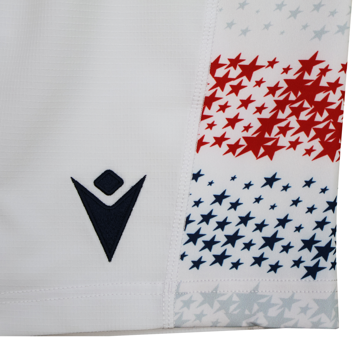 Close-up of USA Rugby 25/26 Home Shorts by Macron, featuring a navy Macron logo on white fabric with bold red and blue stars. Lightweight and breathable, these shorts provide moisture-wicking comfort for peak performance.