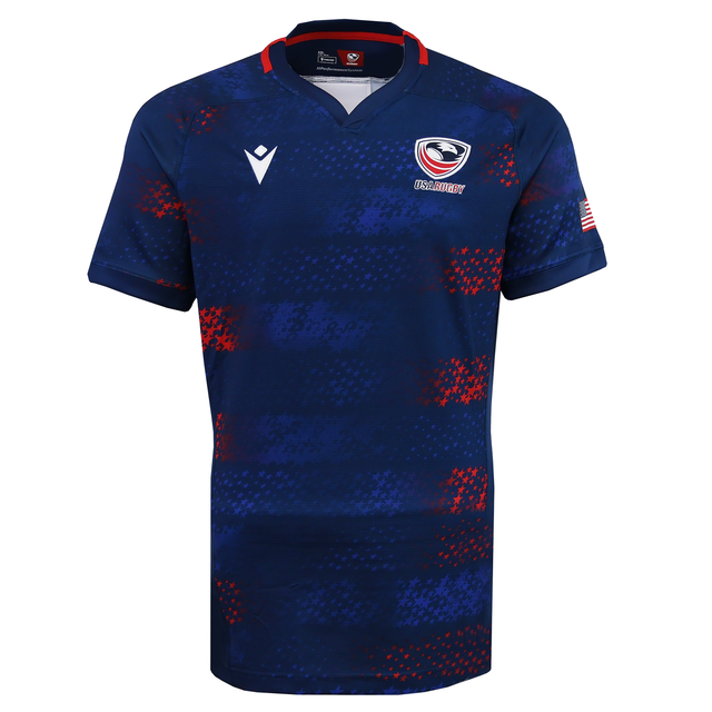 The USA Rugby 25/26 Away Body Fit Match Jersey by Macron features a navy design with red and blue patterns, the official USA Rugby logo on the chest, and an American flag patch on the sleeve.