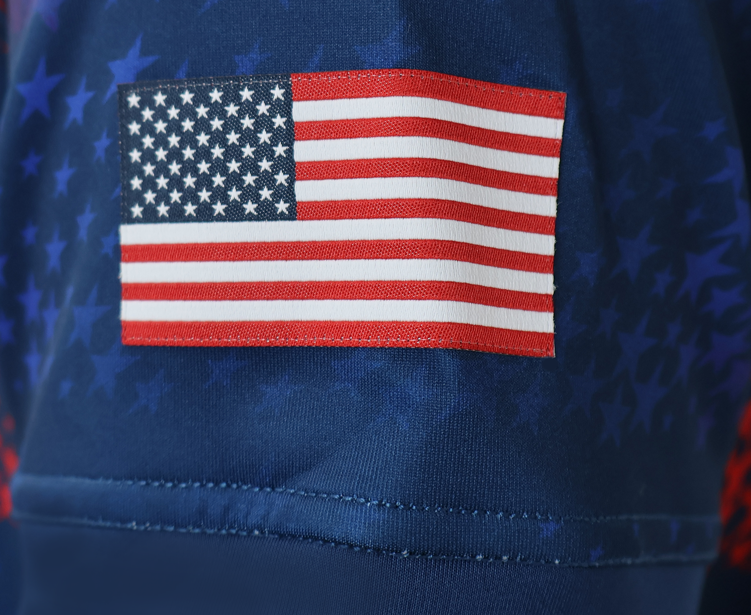 Close-up of an American flag patch sewn onto blue star-patterned fabric on the USA Rugby 25/26 Away Body Fit Match Jersey by Macron, highlighting its patriotic detail and high-performance design.