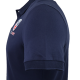Side view of the USA Rugby 25/26 Athleisure Cotton Polo by Macron in dark blue, featuring a ribbed collar, sleeve cuffs, and a small embroidered chest logo for an easy athleisure style.
