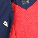 Close-up of the USA Rugby 25/26 Athleisure Softshell Jacket by Macron, navy blue and partially unzipped to show a red zigzag inner lining with visible logo—an ideal water-resistant jacket for athleisure style.