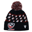 The USA Rugby 25/26 Pompom Beanie by Macron is a black acrylic knit hat featuring white stars, red accents, a top pom-pom, and embroidered USA Rugby and Macron logos on the front cuff.