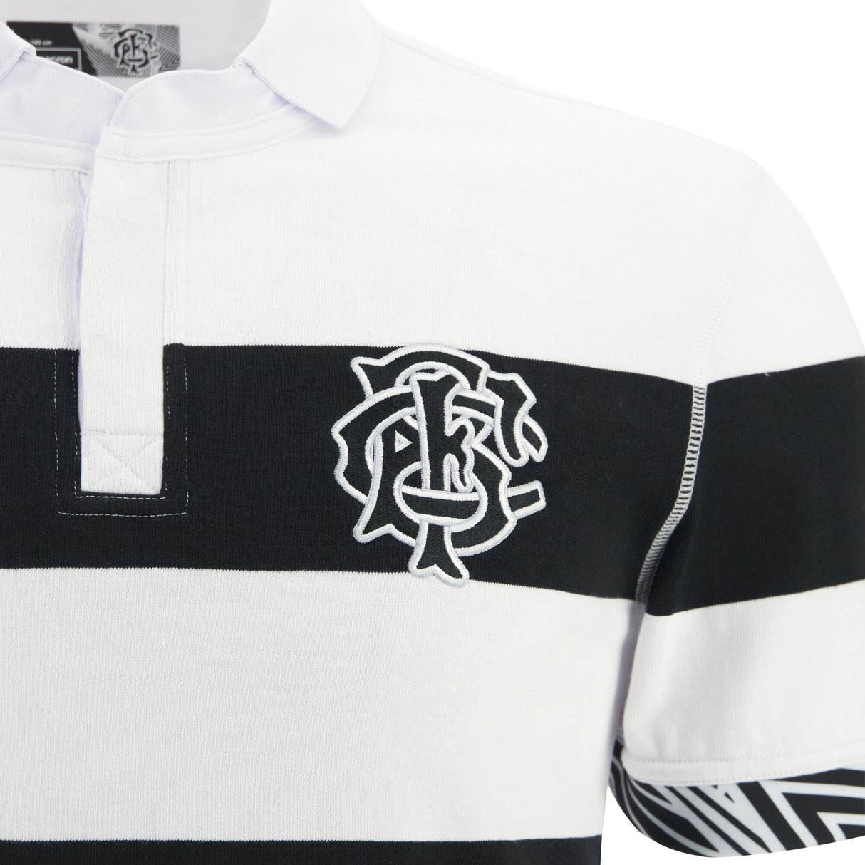 A close-up of the Barbarians 25/26 Cotton Short Sleeve Home Jersey by Macron, featuring black and white stripes, a partial button placket, and a white embroidered logo on the left chest.