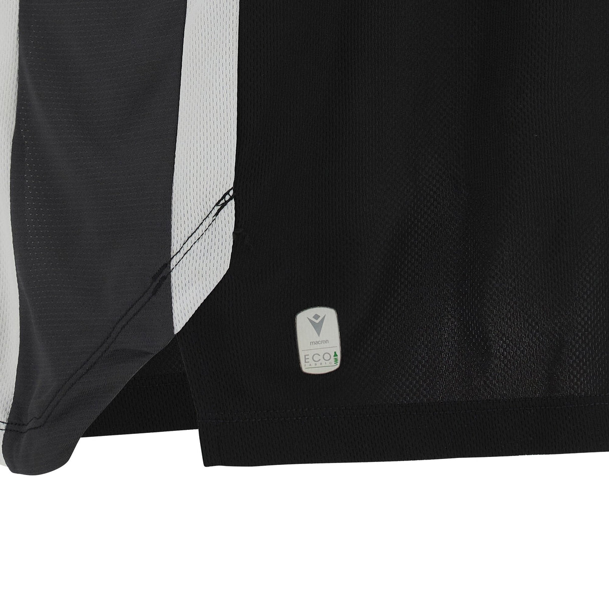 Close-up of the bottom hem of the Barbarians 25/26 Player Training Basketball Singlet by Macron, showing a small "ECO" fabric tag near the edge.