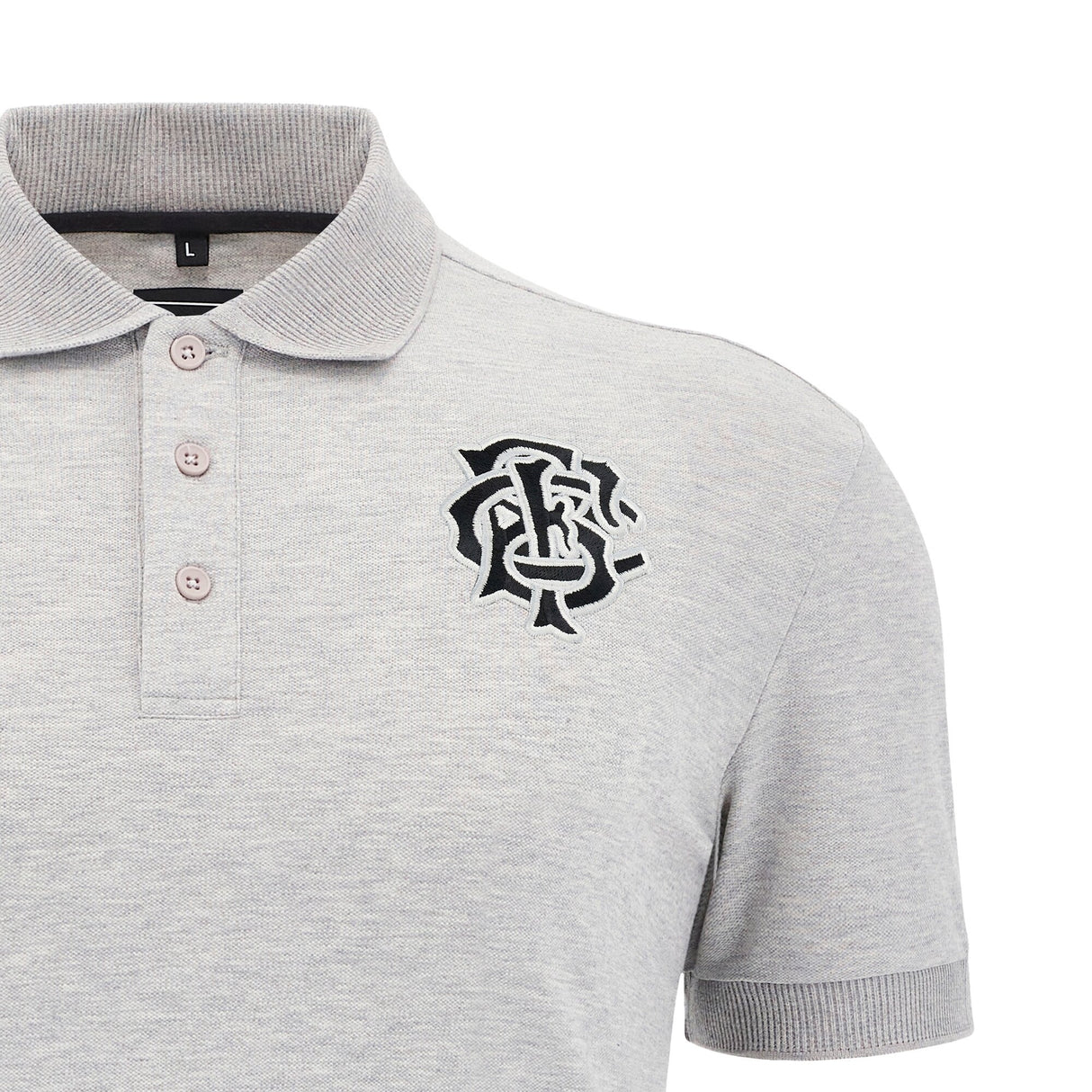 The Barbarians 25/26 Player Travel Polo by Macron is a gray short-sleeve rugby polo with a collar, three buttons, and a black embroidered monogram logo on the left chest.