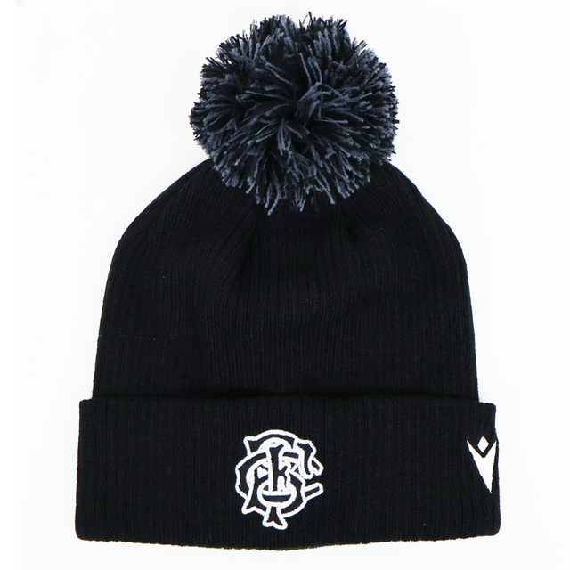 The Barbarians 25/26 Pom-Pom Beanie by Macron features a black knit design with a white embroidered monogram logo and emblem on the cuff, inspired by the classic Barbarians beanie.