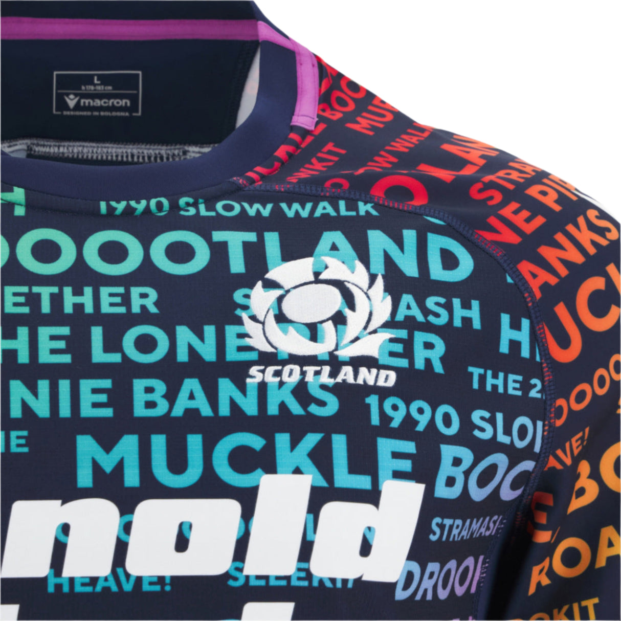 The Scotland 25/26 Rainbow Training Jersey by Macron features vibrant Scottish words and phrases with the team logo, highlighted in a colorful close-up design.