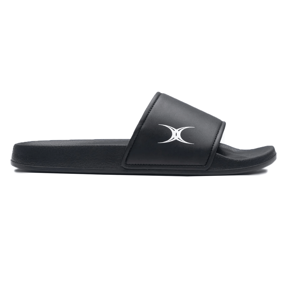 The Gilbert Slide Sandals - Black by Gilbert feature a sleek black design with a wide strap adorned with a white crescent moon logo on the side. They offer exceptional comfort with an arched foam sole and plush cushioning and are made from quick-drying material.