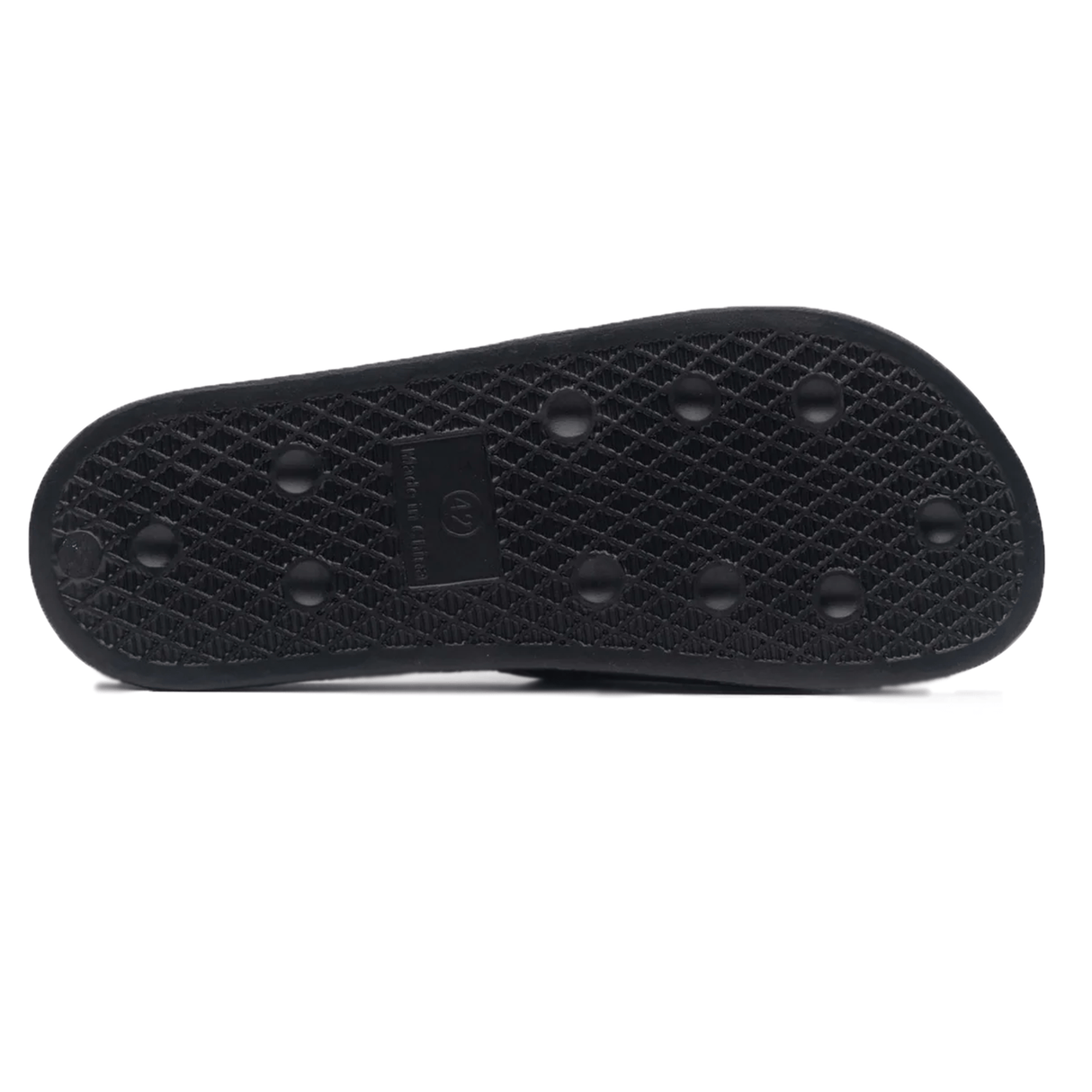 The image shows the sole of a black shoe featuring round grips and a textured pattern for traction, similar to the design found in Gilbert Slide Sandals - Black by Gilbert.