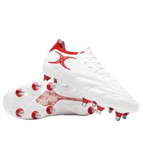 The Gilbert Icon Players 8S - White by Gilbert features white soft ground soccer cleats with red accents and metal studs, ideal for forwards. One shoe stands upright while the other lies on its side.