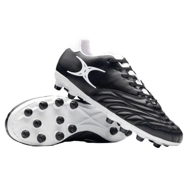 A pair of Sidestep Icon MSX rugby boots by Gilbert in black and white, featuring a synthetic leather upper and a prominent white Gilbert logo—one boot is displayed upright while the other shows the studded sole, designed specifically for firm ground rugby play.
