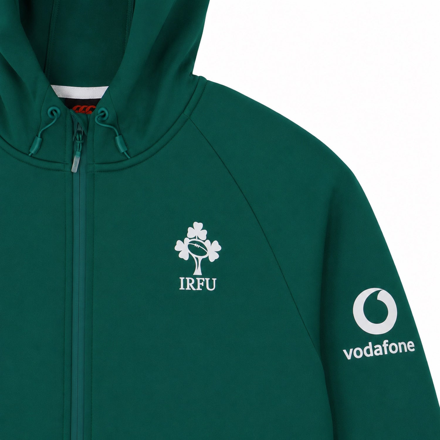 The Ireland 26 Full-Zip Tech Training Hoodie by Canterbury is a green zip-up hoodie featuring the IRFU clover logo on the chest and a Vodafone logo on the sleeve. Visible hood drawstrings add to the sporty finish of this Canterbury training hoodie, shown against a plain white background.