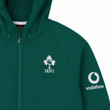 The Ireland 26 Full-Zip Tech Training Hoodie by Canterbury is a green zip-up hoodie featuring the IRFU clover logo on the chest and a Vodafone logo on the sleeve. Visible hood drawstrings add to the sporty finish of this Canterbury training hoodie, shown against a plain white background.