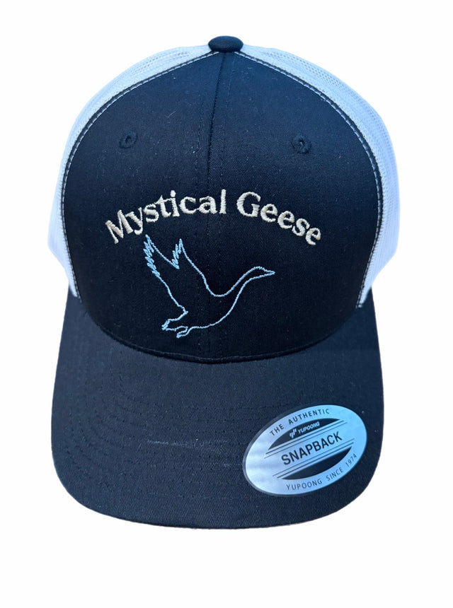 The Mystical Geese Retro Trucker Hat by EMB S&S Activewear features navy and white panels, “Mystical Geese” embroidered text, and a flying goose outline on the front, finished with a classic snapback closure for the perfect fit.