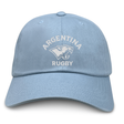 The Nations of Rugby Argentina Dad Cap by EMB S&S Activewear features "Argentina Rugby" text and a puma logo embroidered on light blue cotton twill, making it a stylish choice for fans.