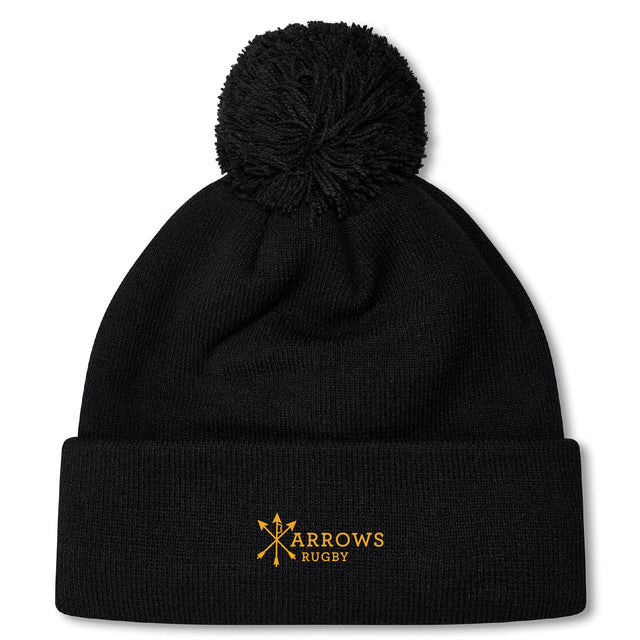 The Arrows Rugby Club Pom Pom Beanie by Canterbury features a black knit, fleece lining, and yellow "Arrows Rugby" logo embroidered on the fold—a cozy EMB Canterbury hat with pom-pom for fans.