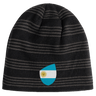 The EMB Canterbury Argentina Shield Beanie features a bold black and grey striped design with an emblem of the Argentine flag.