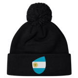 The Argentina Shield Pom Pom Beanie by EMB Canterbury is a black rugby beanie with a pom-pom and an Argentina shield patch on the folded brim.