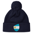 The EMB Canterbury Argentina Shield Pom Pom Beanie in navy blue features a fun patch with a sun-centered flag, adding flair to your winter wardrobe.