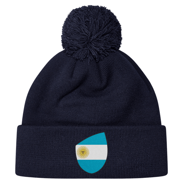The EMB Canterbury Argentina Shield Pom Pom Beanie in navy blue features a fun patch with a sun-centered flag, adding flair to your winter wardrobe.