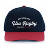 The EMB Augusta USA Rugby Elevated 1975 Eagles Snapback Cap features navy blue and red colors with "EST MCMLXXV Usa Rugby" in white script, ideal for fans who love vintage style and rugby tradition.