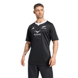 A person wearing the Black Ferns 24/25 Home Supporters Jersey by adidas, featuring AEROREADY technology and white logos, stands against a plain background.
