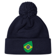 The EMB Canterbury Brazil Shield Pom Pom Beanie in navy blue features a colorful green and yellow patch with a map design, topped with a playful pom pom.