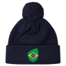 The EMB Canterbury Brazil Shield Pom Pom Beanie in navy blue features a colorful green and yellow patch with a map design, topped with a playful pom pom.