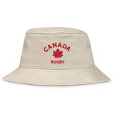 The EMB S&S Activewear Nations of Rugby Canada Rugby Crusher Bucket Hat is a beige cotton twill bucket hat with "Canada Rugby" and a red maple leaf embroidered on the front.