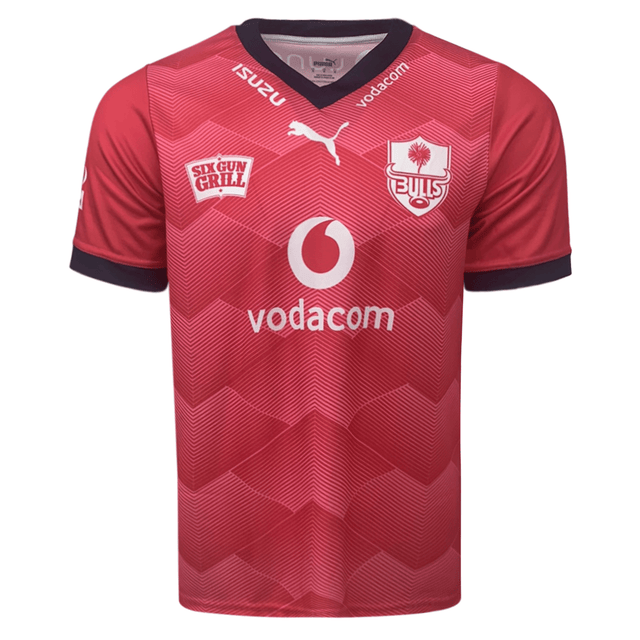Front of light red with gradient accents jerseys. Vneck style collar with Izuzu & vodacom in white on the rim of the collar. white Puma logo center just below neck. Bulls logo on the left chest and Six Gun Frill on the right chest. Big Vodacom logo center front in white and red.