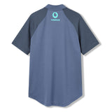 The Ireland 26 Poly Polo by Canterbury is a short-sleeved blue polo featuring dark blue sleeves and a light blue Vodafone logo on the upper back, designed in the classic style of an Ireland rugby polo.