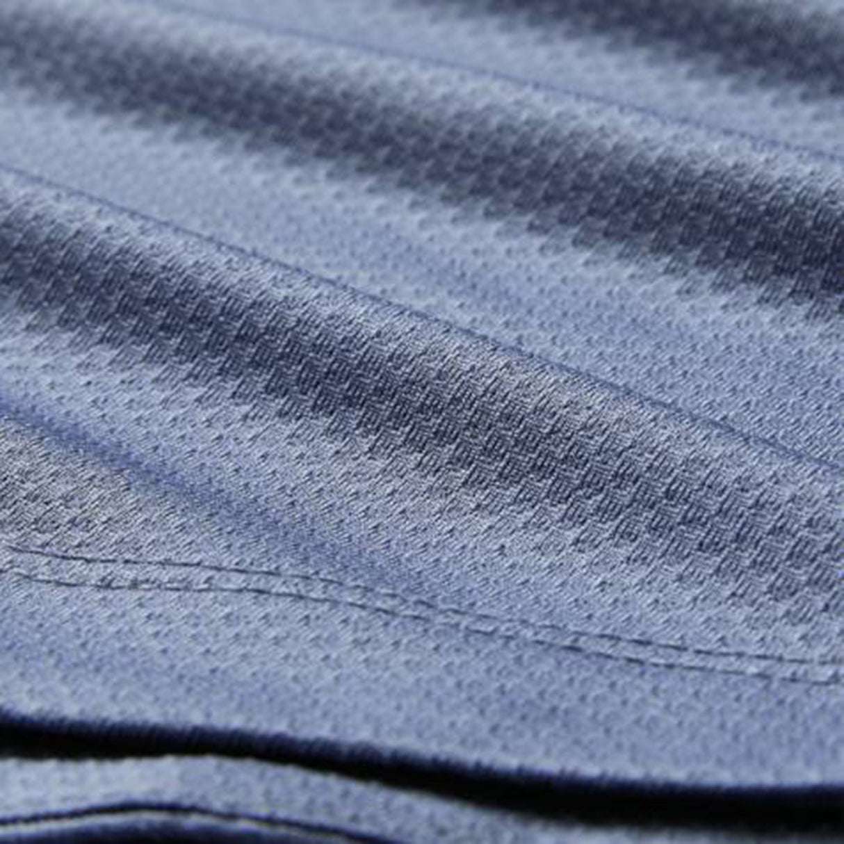 Close-up of blue textured fabric with visible stitching and a subtle diagonal pattern, similar to the premium quality featured in the Ireland 26 Poly Polo by Canterbury.