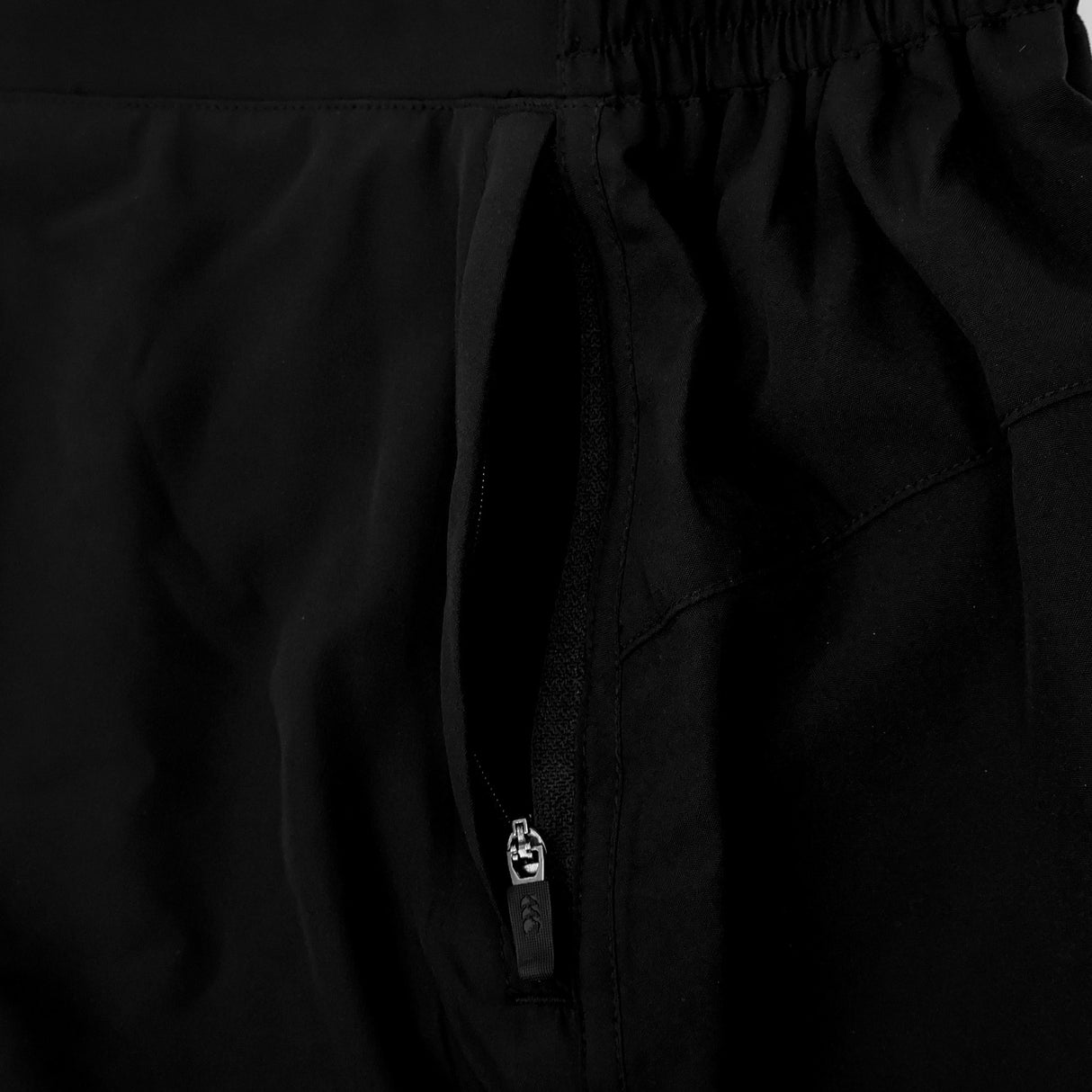 Close-up of the Ireland 26 5″ Woven Gym Short by Canterbury in black, featuring an open zippered pocket and an elastic waistband, highlighting the material texture and stitching details.