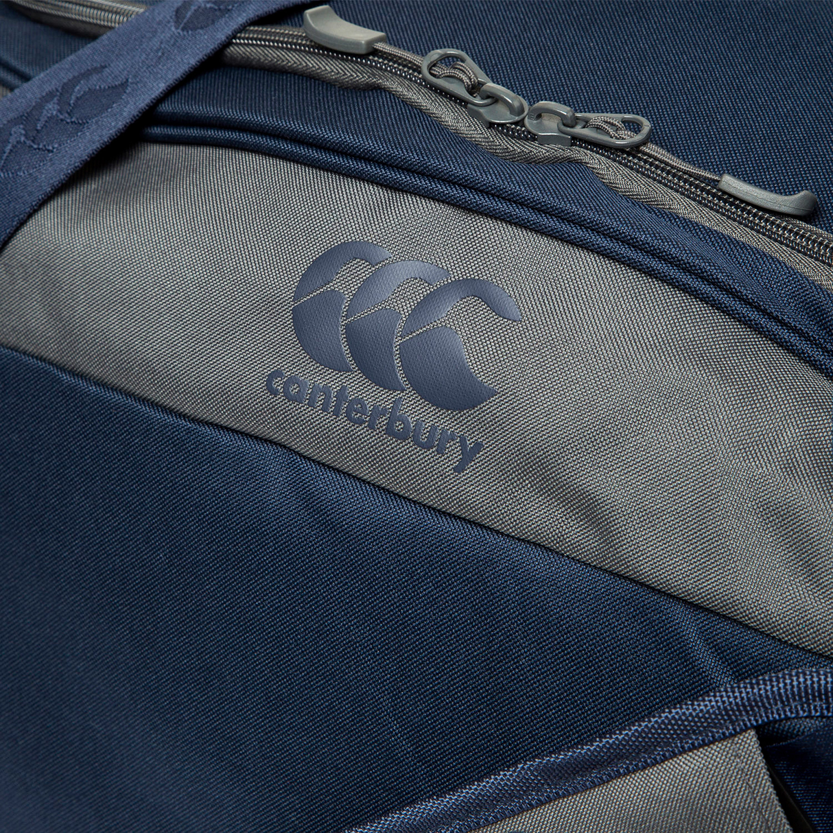 Close-up of the Canterbury Holdall Duffle Bag in navy blue and gray, featuring the Canterbury logo, a zippered pocket, and water-repellent material—ideal for carrying rugby gear.