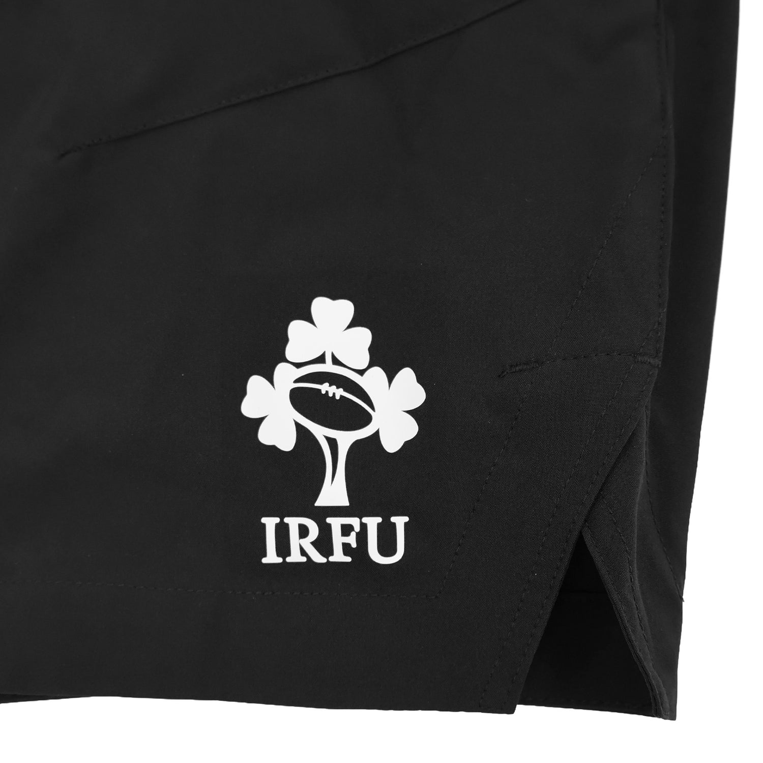 Close-up of a black Ireland 26 5″ Woven Gym Short by Canterbury, featuring the IRFU logo—which includes a shamrock and a rugby ball—printed in white on the fabric.
