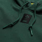Close-up of the Ireland 26 Leisure Hoodie by Canterbury, featuring a dark green design with a logo patch displaying a shamrock, “IRFU,” and a stylized animal—this leisure hoodie is perfect for fans who value comfort and team spirit.