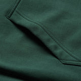 A close-up of the Ireland 26 Leisure Hoodie by Canterbury in forest green, showcasing the pocket’s textured fabric and double-stitched seams—a testament to Canterbury’s renowned quality craftsmanship.