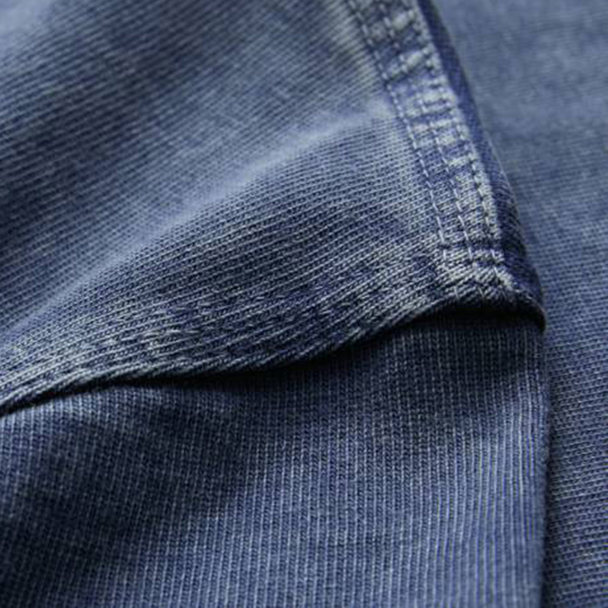 Close-up of blue denim fabric, highlighting the texture and intricate stitching along the seam—evoking the premium craftsmanship featured in Canterbury’s Ireland 26 Premium OS Washed T-shirt.
