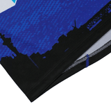 A close-up of the Blues Super Rugby Home Jersey 24 by Classic Sportswear shows a blue and black design with a white edge, city skyline silhouette, and towers. Made from moisture-wicking fabric, it's ideal for Super Rugby fans seeking comfort and style.