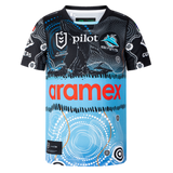 The Sharks Indigenous NRL 25/26 Replica Jersey by Classic Sportswear features Indigenous-inspired black, blue, and white patterns, with "Aramex" and "Pilot" sponsor logos on the front and the Sharks team logo on the chest.